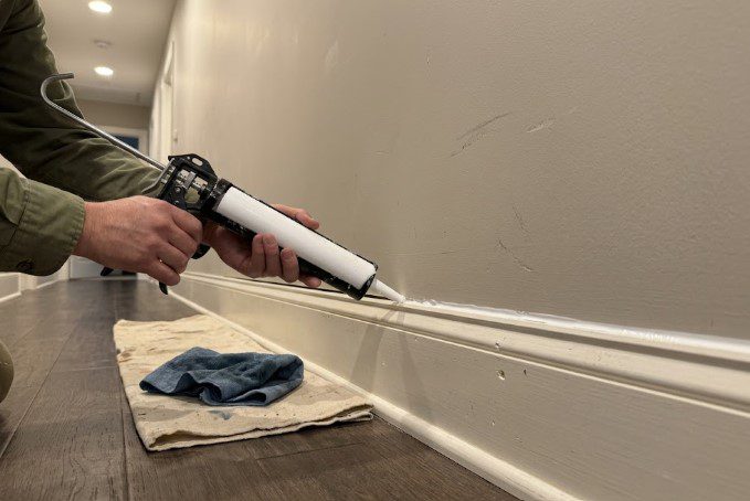 Painter caulking a corner board joint on a Richmond house before painting
