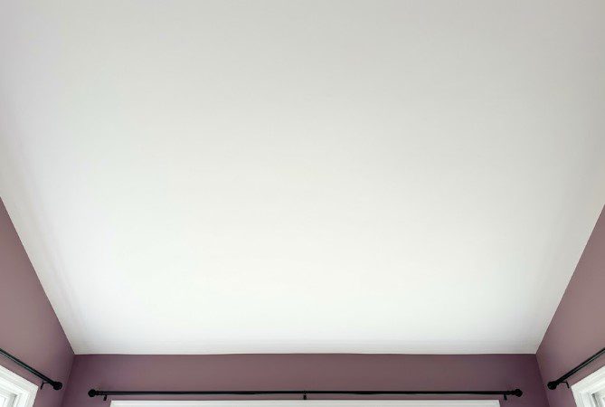 Evenly painted white ceiling above mauve walls in a sunlit room with three windows